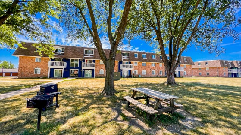 Community picnic and grill area under mature trees at The Hampton Meadows